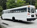 A 2015 Spartan School Bus with a white exterior and large windows is shown from a rear angle highlighting its sleek design and black wheels