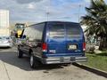 A blue 2011 Ford Econoline van parked with the rear view visible showing a plain license plate area and chrome accents