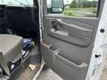 A 2014 GMC Savana with an open driver's door displaying the interior panel and a driver's seat with items on the floor and in the door's storage compartment