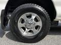 Close-up of a silver alloy wheel on a 2003 Mitsubishi Delica featuring a rugged tire design with detailed treads and a shiny center cap showing the Mitsubishi logo