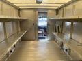 Interior of a 2012 Ford Econoline with metal shelves on each side and a view of the driver's seat and door at the rear