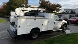 A white 2007 Ford F-550 service truck with a utility body and a cherry picker mounted on top