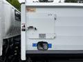 A white 2014 Hino 195 truck with a visible back door and warning signs attached to the side of the body