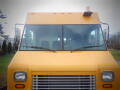 Front view of a yellow 2008 Freightliner MT45 Chassis featuring large windows and a horizontal grille with a light on the roof