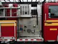 A 2009 Spartan Gladiator fire truck featuring a metallic pump panel with various controls hoses and connections displayed prominently on the side