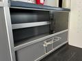 A 2013 Chevrolet Express with storage compartments featuring a microwave and a metal rack for supplies
