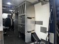 A 2020 Ford Transit interior featuring metal storage compartments including shelves and dividers with straps attached