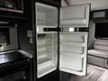 Interior view of an empty refrigerator with an open freezer compartment inside a 2022 Aspen Trail travel trailer