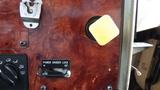 A close-up view of the dashboard controls of a 2003 International 5600i featuring a power divider lock switch and a yellow knob against a wood grain panel