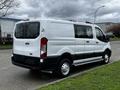 A white 2023 Ford Transit van viewed from the rear with sliding doors and a high roof