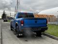 A blue 2021 RAM 1500 Classic pickup truck is parked on the road with dual exhaust pipes visible at the rear