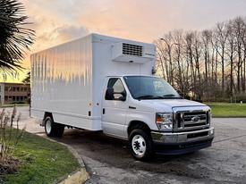 A white 2021 Ford Econoline van with a refrigerated box on the back parked at an angle