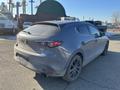 A gray 2023 Mazda MAZDA3 hatchback with a sporty design and dark wheels, showing signs of dirt on the surface