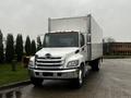 A white 2020 Hino 338 box truck with chrome accents and a large cargo area in the back positioned at an angle on the road