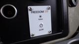 Close-up of a control panel featuring a status indicator light and an On/Off button labeled Freedom SW