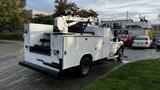 A 2007 Ford F-550 utility truck with a white body featuring tool storage compartments and a mounted bucket lift on the rear