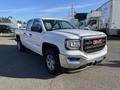 A 2018 GMC Sierra 1500 in white with chrome accents featuring a prominent grille and sleek body design parked at an angle