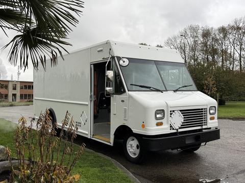 A white 2011 Ford Econoline delivery truck with a boxy design and large front grille parked at an angle with its door open