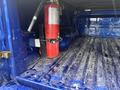 A red fire extinguisher mounted in the cargo bed of a blue 2019 RAM 1500 Classic with a dirty textured surface