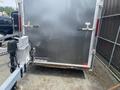 A gray 2020 Stealth Enterprises trailer with a smooth exterior and two doors at the rear showing locks and a logo on the lower side