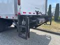A 2015 Freightliner M2 106 with a tail lift mechanism attached to the back featuring a robust frame and hydraulic arms for loading and unloading cargo