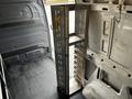 A metal tool organizer with multiple shelves and a hook, positioned upright in the cargo area of a 2020 Mercedes-Benz Sprinter van