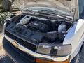 A 2020 Chevrolet Express with its hood raised revealing the engine compartment and various components including the battery and coolant reservoir