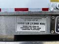 A steel sign on a lifting platform stating the maximum capacity of 3000 pounds or 1360 kilograms when the load is centered on the load carrying platform