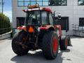 A 2011 Kubota M8540D tractor with large rear tires and a distinctive orange and black color scheme featuring a cab and attached rear implement