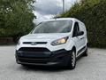 A white 2014 Ford Transit Connect van is parked with a black front grille and wheels visible. The vehicle has sliding side doors and a streamlined design for commercial use