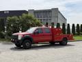 A red 2013 Ford F-550 truck with a flatbed and utility boxes on the sides parked on a paved surface