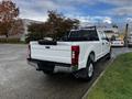 A white 2020 Ford F-250 Super Duty truck parked with a black bed cover and rear grid guard