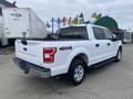 A white 2019 Ford F-150 pickup truck with a black bed liner and chrome accents parked with the tailgate down