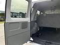 Interior view of a 2014 Ford Econoline van showing an open side door and rear seating area with a grey bench seat and floor carpet