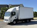 A white 2013 Isuzu NPR box truck with a clear cargo area and a streamlined cab design featuring orange lights on the roof