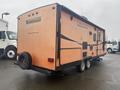 A 2015 Winnebago of Indiana travel trailer with an orange exterior featuring black accents and two axles