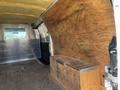 Interior view of a 2012 Chevrolet Express van showing plywood and metal paneling with a wooden storage box on the floor