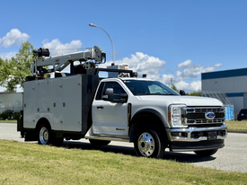 A 2023 Ford F-550 truck with a utility body and an elevated work platform mounted on the back