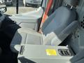 A plush gray driver's seat in a 2016 Ford Transit with a foldable armrest and storage compartment