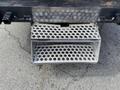 A metal step attached to the rear of a 2015 Ford F-550 with a perforated design for traction