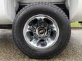 A close-up of a chrome wheel rim with a Chevrolet logo and a rugged tire of a 2013 Chevrolet Silverado 3500HD