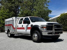 A white 2009 Ford F-550 truck with red and silver accents features a service body and dual rear wheels parked at an angle