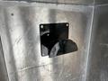 A black circular receptacle mounted on a silver metallic surface with four screw holes visible