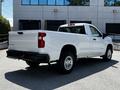 A white 2021 Chevrolet Silverado 1500 pickup truck is parked with a standard cab and a bed, showcasing its rear and side profile