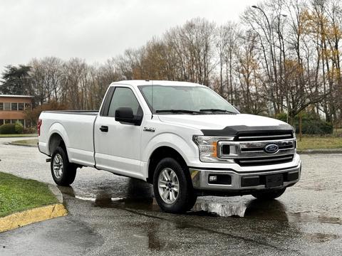 A white 2018 Ford F-150 parked with a single cab and standard bed featuring a chrome front grille and alloy wheels