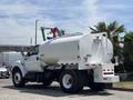 A 2015 Ford F-750 water truck with a large white tank mounted on the rear and a hose attachment at the top