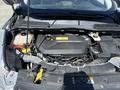 The engine compartment of a 2014 Ford Escape with a visible engine block battery reservoir and various components including hoses and a dipstick