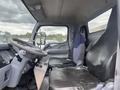 The interior of a 2008 Mitsubishi Fuso FE180 featuring a driver's seat and a passenger seat with black fabric covering and a dashboard with controls