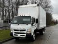 A 2021 Mitsubishi FE box truck with a white exterior and orange roof markers parked on the street