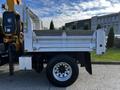 A 2013 International DuraStar 4300 truck with a flatbed and raised dump feature parked on a concrete surface